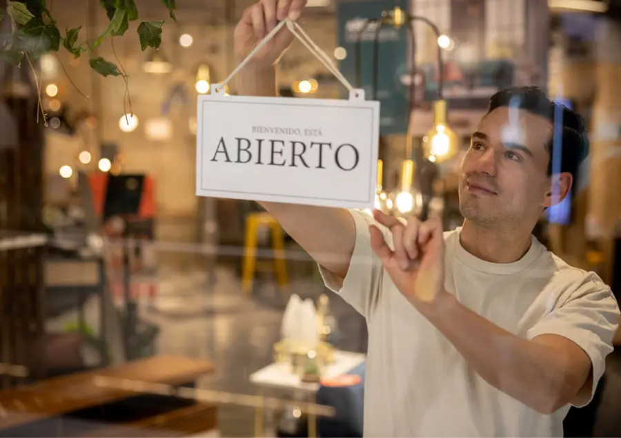 Comerciante colgando el cartel de abierto en su local recién habilitado